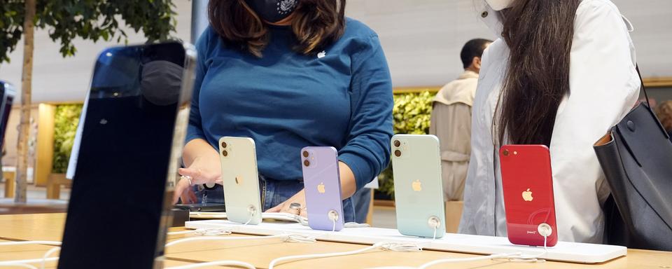 Une employée d'un magasin Apple (gauche) présente des iPhone à une cliente à New York le 24 septembre 2021. [Keystone - AP Photo/Richard Drew]