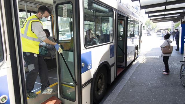 Une homme nettoie un bus pendant la pandémis de Covid-19. [Keystone - Laurent Gillieron]