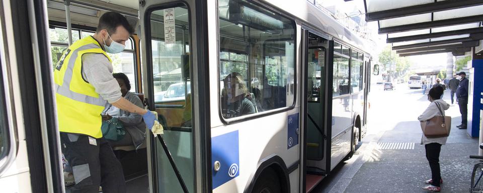 Une homme nettoie un bus pendant la pandémis de Covid-19. [Keystone - Laurent Gillieron]