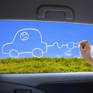 Un enfant dessine une voiture électrique sur la fenêtre d'une voiture. [Depositphotos - tomwang]