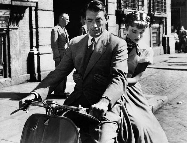 Les acteurs Gregory Peck et Audrey Hepburn à bord d'une Vespa dans le film "Vacances romaines", en 1953. [KEYSTONE - Photopress-Archiv]