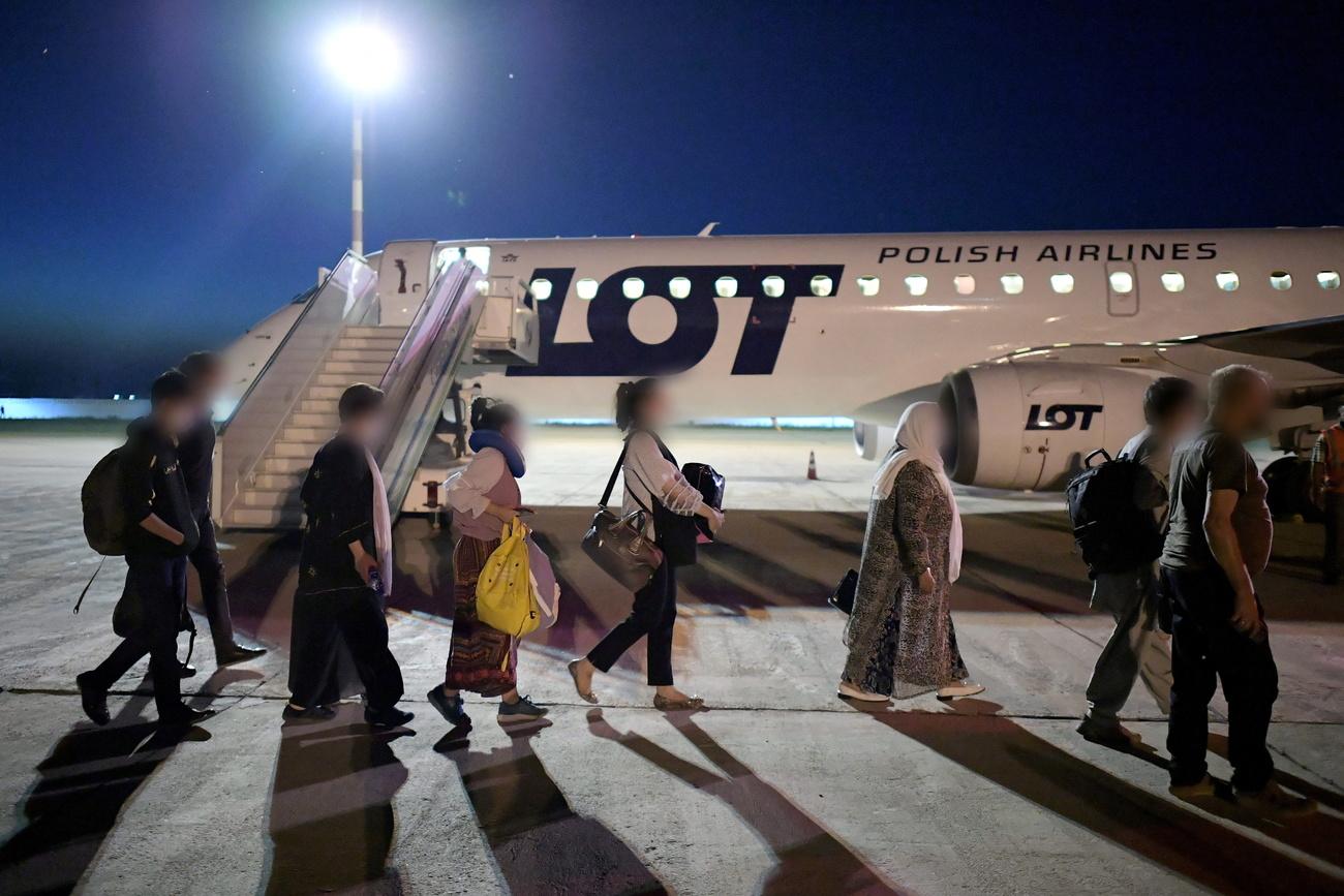 Des personnes évacuées de Kaboul sont dirigées vers un avion à destination de Varsovie, le 20 août 2021 en Ouzbékistan. [EPA/Keystone - Marcin Obara]