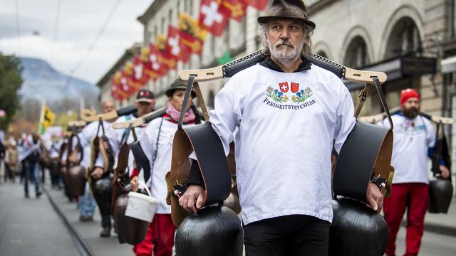 Des personnes manifestent à Genève contre la loi Covid-19 avec la présence des sonneurs de cloche. [Keystone - Jean-Christophe Bott]