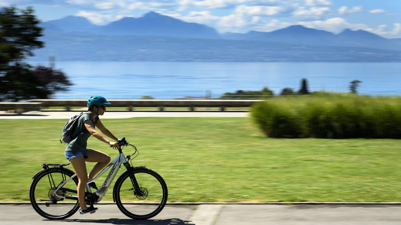 Une personne à vélo électrique sur l'esplanade de Montbenon à Lausanne. [Keystone - Laurent Gillieron]