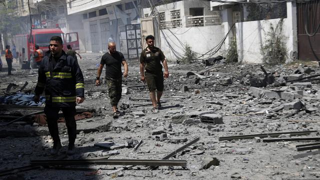 Les pompiers inspectent un bâtiment détruit à Gaza à la recherche de victimes. [Keystone - AP Photo/Adel Hana]