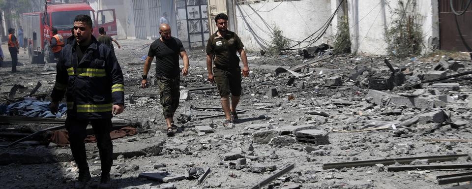 Les pompiers inspectent un bâtiment détruit à Gaza à la recherche de victimes. [Keystone - AP Photo/Adel Hana]