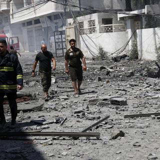Les pompiers inspectent un bâtiment détruit à Gaza à la recherche de victimes. [Keystone - AP Photo/Adel Hana]