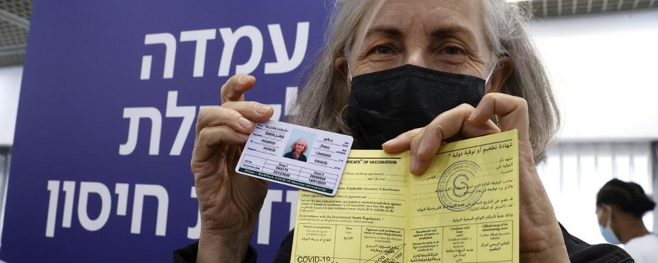 Une travailleuse médicale présente sa carte internationale et son certificat de vaccination contre le Covid-19. Tel-Aviv, le 14 janvier 2021. [AFP - Jack Guez]