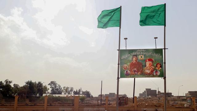 Un panneau d'affichage faisant l'éloge du leader assassiné Mouammar Kadhafi et un drapeau de l'ère Kadhafi sont visibles dans la ville de Bani Walid, le 14 octobre 2021. [AFP - Mahmud Turkia]