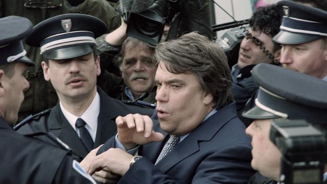 Bernard Tapie sort du tribunal de Valenciennes en 1995, escorté par la police. [AFP - Thomas Coex]