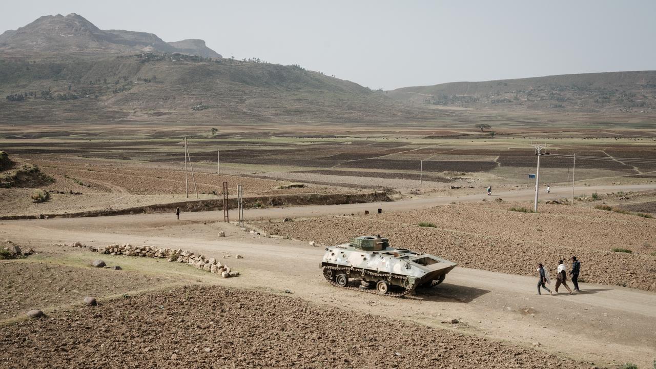 Des gens marchent près d'un char de l'armée éthiopienne abandonné sur la route près de Dengolat, au sud-ouest de Mekele dans la région du Tigré, en Éthiopie. [AFP - Yasuyoshi Chiba]
