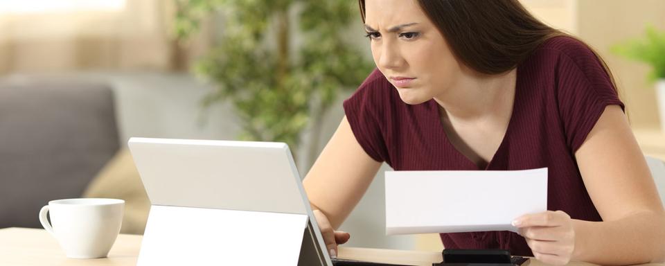 Une femme a l'air contrariée alors qu'elle consulte sa tablette. [Depositphotos - AntonioGuillemF]