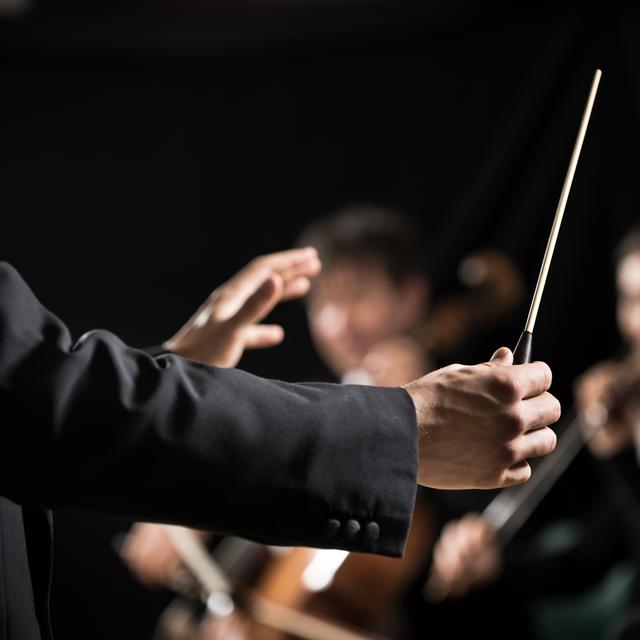 Une personne conduisant et dirigeant un orchestre symphonique (image prétexte). [Depositphotos - stokkete]