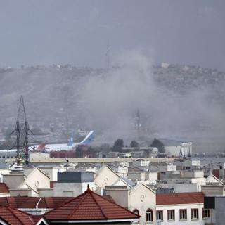 De la fumée est visible depuis l'extérieur de l'aéroport de Kaboul, où une explosion a eu lieu et aurait fait plusieurs victimes. [Keystone - Wali Sabawoon]