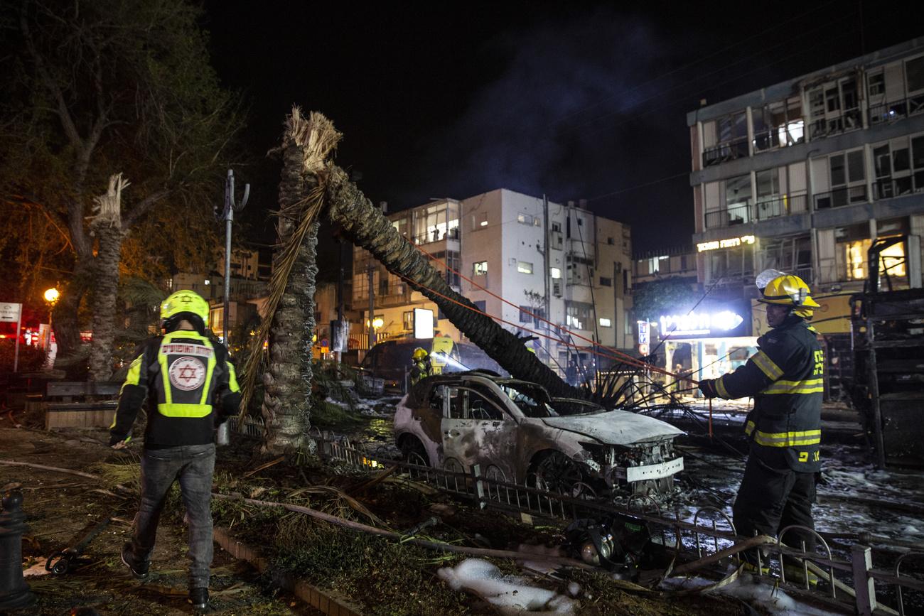 Des pompiers israéliens à l'oeuvre sur le site d'impact d'une roquette à Tel Aviv, le 11 mai 2021. [Keystone - Heidi Levine]