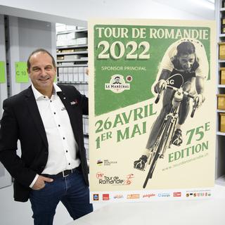 Richard Chassot, directeur du Tour de Romandie, pose avec l'affiche du TDR 2022 dans les archives cantonales valaisanne lors de la présentation à la presse de la 75e édition. [Laurent Gillieron]