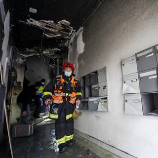 Un sapeur pompier volontaire, sort de l'allée où l'incendie a prit dans un immeuble à la rue Royaume, ce dimanche 10 janvier 2021 à Genève. [KEYSTONE - MARTIAL TREZZINI]