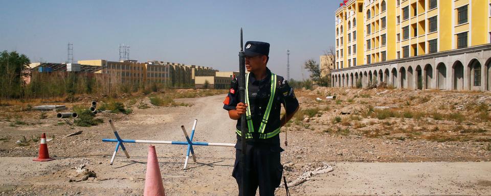 Un policier chinois garde une route près d'un "centre de formation professionnelle" dans le Xinjiang. [Reuters - Thomas Peter]