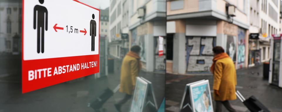 Un panneau priant de respecter les distances à Bonn, en Allemagne. [Keystone - DPA/Oliver Berg]