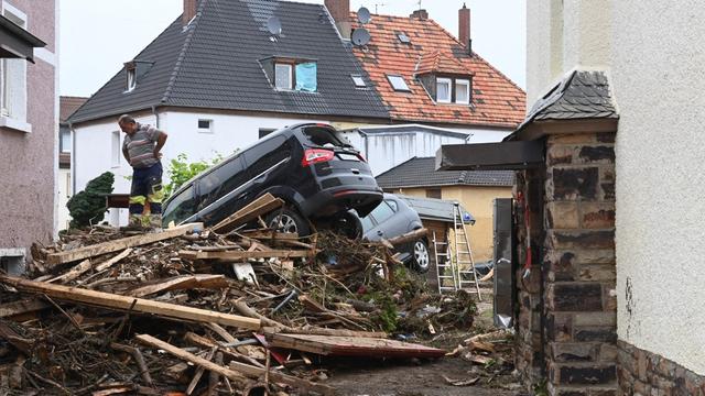 Un homme se tient à côté de débris empilés et de voitures endommagées dans une rue de Bad Neuenahr-Ahrweiler, dans l'ouest de l'Allemagne, le 16 juillet 2021. [AFP - Christof Strache]