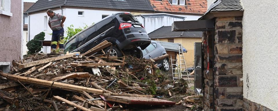 Un homme se tient à côté de débris empilés et de voitures endommagées dans une rue de Bad Neuenahr-Ahrweiler, dans l'ouest de l'Allemagne, le 16 juillet 2021. [AFP - Christof Strache]