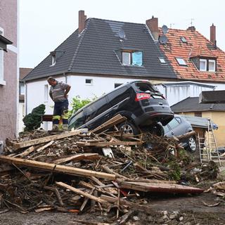 Un homme se tient à côté de débris empilés et de voitures endommagées dans une rue de Bad Neuenahr-Ahrweiler, dans l'ouest de l'Allemagne, le 16 juillet 2021. [AFP - Christof Strache]
