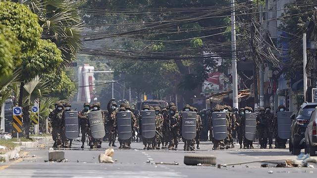 Des soldats birman avancent derrière des boucliers en direction de la foule dans une rue de Rangoun, capitale de la Birmanie, le 2 mars 2021. [AP/Keystone]