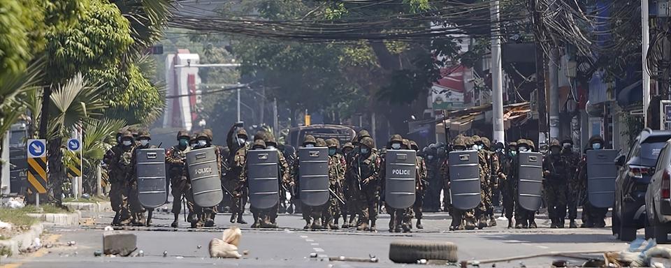 Des soldats birman avancent derrière des boucliers en direction de la foule dans une rue de Rangoun, capitale de la Birmanie, le 2 mars 2021. [AP/Keystone]