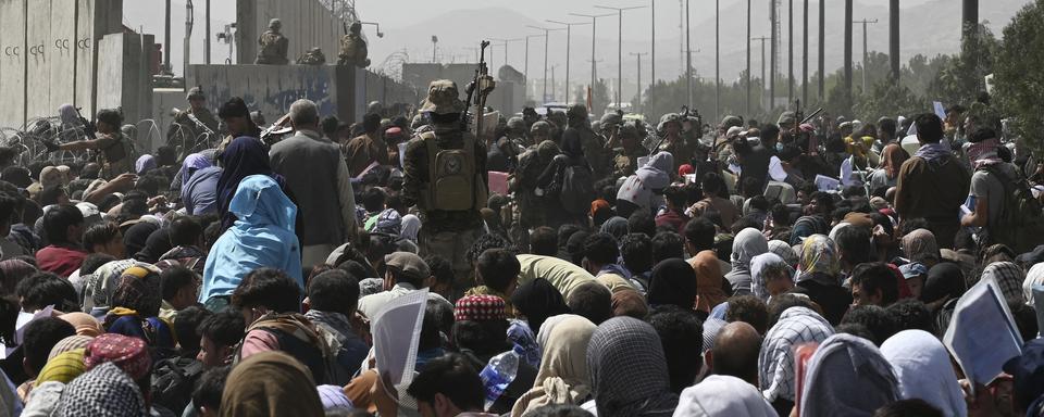 Des milliers d'Afghans se pressent autour de l'aéroport militaire de Kaboul, le 20 août 2021. [AFP - Wakil Kohsar]