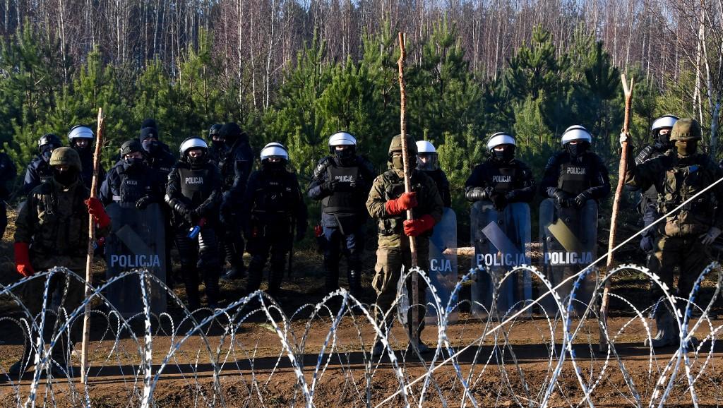 Des policiers polonais gardent la frontière près d'un camp de migrants à la frontière biélorusse-polonaise, dans la région de Grodno, en Biélorussie. [AFP - Viktor Tolochko / Sputnik]