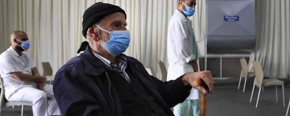 Un homme attend de recevoir une dose de vaccin dans un hôpital au Liban. [Keystone/AP Photo - Hussein Malla]