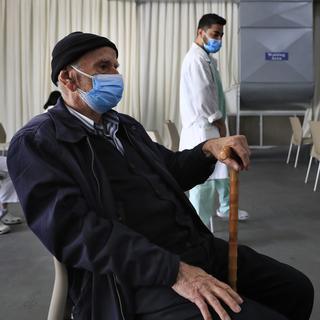 Un homme attend de recevoir une dose de vaccin dans un hôpital au Liban. [Keystone/AP Photo - Hussein Malla]