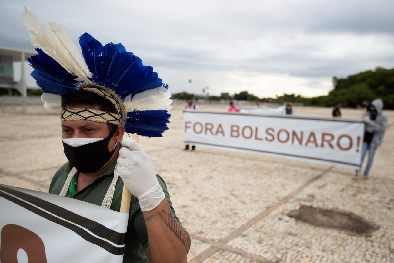 "Bolsonaro dehors!" proclame la banderole de ces personnes indigènes. Elles demandent la démarcation de leurs terres et la démission du président Jair Bolsonaro. Brasilia, le 19 avril 2021. [Keystone/epa - Joedson Alves]
