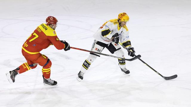 Le defenseur valaisan Goran Bezina (à gauche) lutte pour le puck avec le Top-Scorer jurassien Philip-Michael Devos (à droite). [Cyril Zingaro]