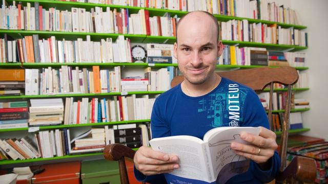 Le philosophe et écrivain Alexandre Jollien pose devant sa bibliothèque. [KEYSTONE/Jean-Christophe Bott]