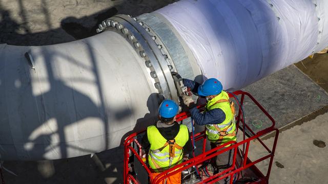 Des ouvriers installes des conduites d'eau sur le chantier de GeniLac, à Genève. [KEYSTONE - Salvatore Di Nolfi]