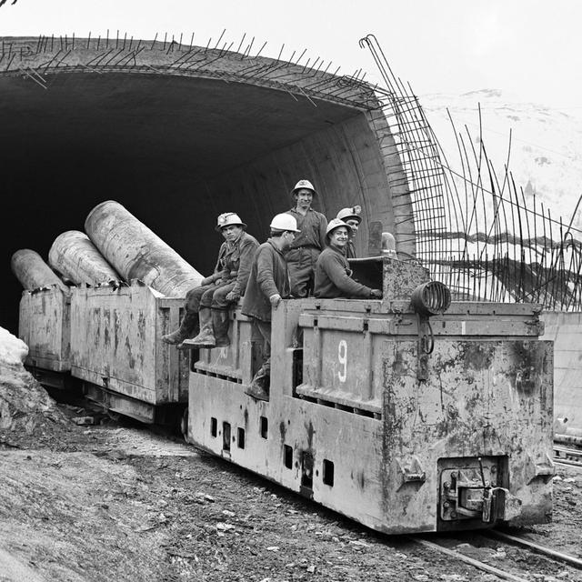 Des mineurs sur un wagonnet à l'entrée nord du tunnel du San Bernardino, dans le canton des Grisons, le 7 avril 1965. D'une longueur de 6,6 km, l'ouvrage sera terminé en 1967 après six ans de travaux. [KEYSTONE/ PHOTOPRESS-ARCHIV - Ernst Baumann]