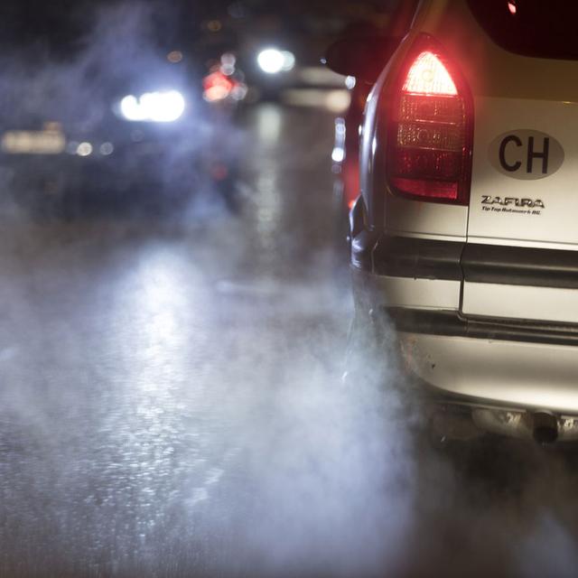 Gros plan sur le phare arrière d'une voiture qui roule la nuit. [Keystone - Gaetan Bally]