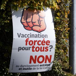 Une affiche sur laquelle est écrit: "Vaccination forcée pour tous ? Non au durcissement extrême et inutile de la loi Covid". [Keystone - Laurent Gillieron]