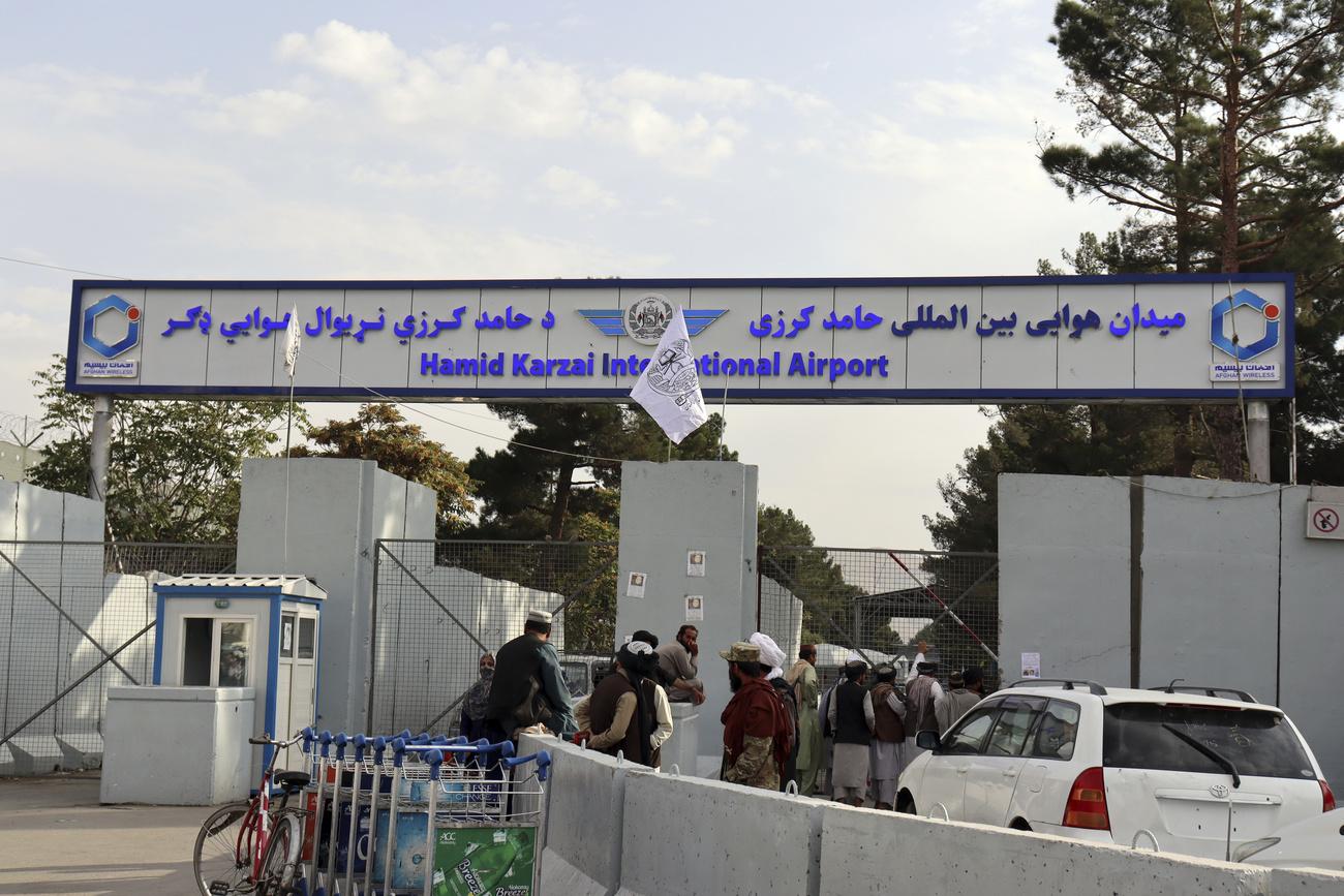 Des talibans devant le stand de sécurité à l'entrée de l'aéroport de Kaboul. [Keystone - AP Photo/Khwaja Tawfiq Sediq]