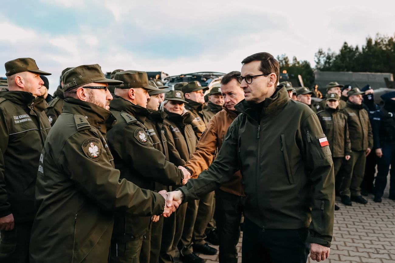 Le Premier ministre polonais Mateusz Morawiecki (à droite) lors d'une réunion avec des soldats et des officiers des services chargés de sécuriser la frontière polonaise avec la Biélorussie dans la région de Kuznica, dans l'est de la Pologne, le 9 novembre 2021. [KEYSTONE - Adam Guz / EPA / Chancellerie du Premier ministre polonais]