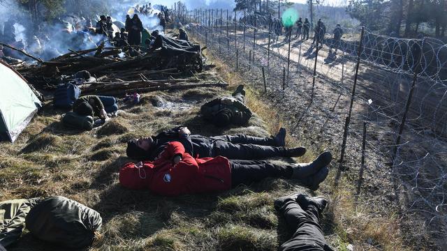 Des réfugiés gisent sur le sol dans un camp de migrants à la frontière entre la Pologne et la Biélorussie. [AFP - Viktor Tolochko / Sputnik]