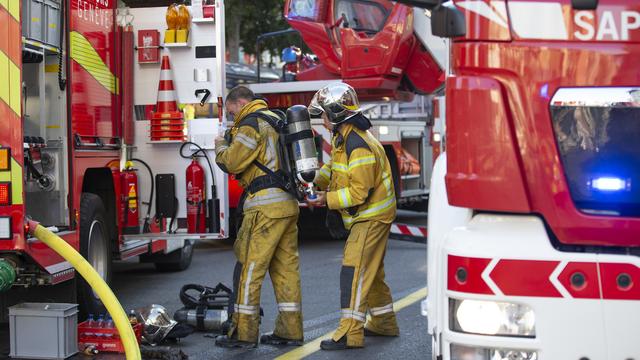 Des pompiers du Service d'incendie et de secours (SIS) se préparent pour intervenir sur la toiture d'un immeuble de la rue l'Arquebuse suite a l'incendie d'un appartement, ce dimanche 29 août 2021 a Genève. [KEYSTONE - Salvatore Di Nolfi]