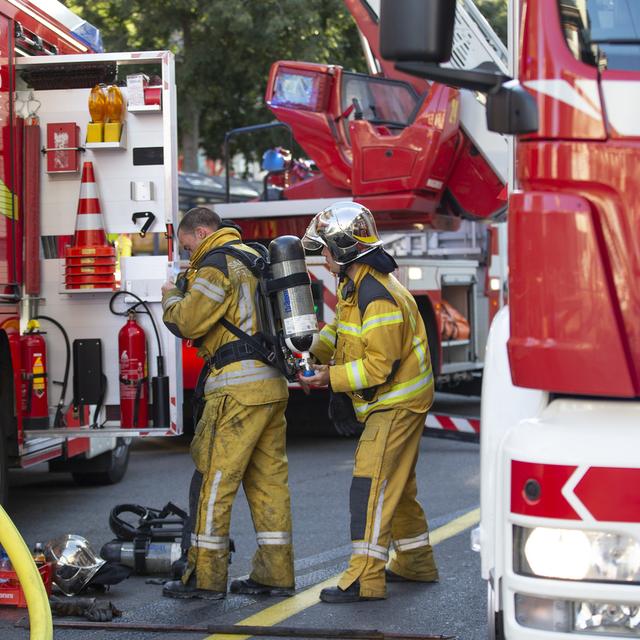 Des pompiers du Service d'incendie et de secours (SIS) se préparent pour intervenir sur la toiture d'un immeuble de la rue l'Arquebuse suite a l'incendie d'un appartement, ce dimanche 29 août 2021 a Genève. [KEYSTONE - Salvatore Di Nolfi]