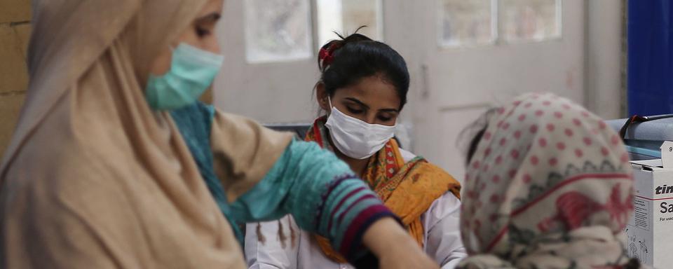 Une femme recevant une dose de vaccin contre le coronavirus dans un centre de Karachi au Pakistan. [EPA/Keystone - Shahzaib Akber]