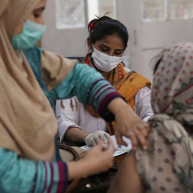 Une femme recevant une dose de vaccin contre le coronavirus dans un centre de Karachi au Pakistan. [EPA/Keystone - Shahzaib Akber]