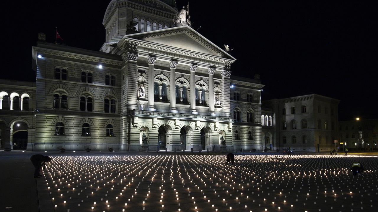 9200 bougies ont été allumées dimanche 21 février sur la Place fédérale à Berne, une par victime du Covid. [Keystone - EPA/Peter Schneider]