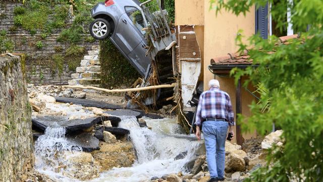 Une carcasse de voiture à la verticale contre une maison de Cressier (NE). [Keystone - Laurent Gillieron]