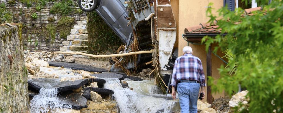 Une carcasse de voiture à la verticale contre une maison de Cressier (NE). [Keystone - Laurent Gillieron]