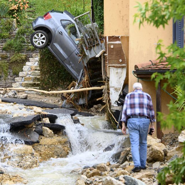 Une carcasse de voiture à la verticale contre une maison de Cressier (NE). [Keystone - Laurent Gillieron]